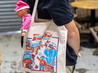 Man holding a tote bag with children's toys in it
